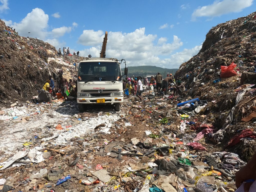 Waste pickers crowding waste truck arriving at Pugu Kinyamwezi dumpsite, Dar Es Salaam.